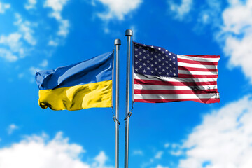 Flags of America and Ukraine on the wind against blue sky