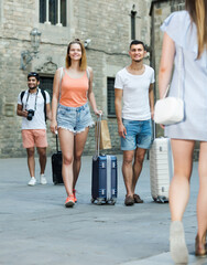 Obraz premium Young couple in shorts with luggage walking through city street