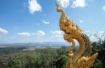 Golden Naga statue with tranquility view of nature in rural Thailand. Nagas are the serpent...