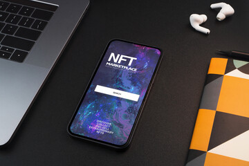 Smartphone with NFT (Non-Fungible Token) Marketplace on the screen on black background table....