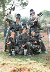 Portrait of happy paintball players wearing uniform and holding guns ready for playing outdoor.