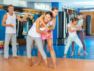 Determined Asian woman sparring with young female opponent in self defense training, trying to...