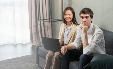 Young businessman and businesswoman working computer or laptop, looking at camera, copy space at background, focus man. Young man and woman work business in home office and copy space background