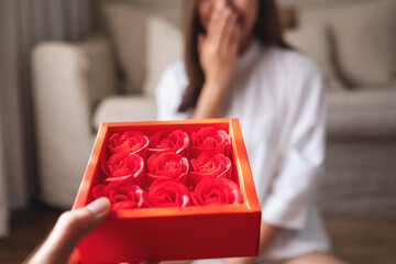 Blurred of a surprised young women receiving red roses in a gift box from boyfriend