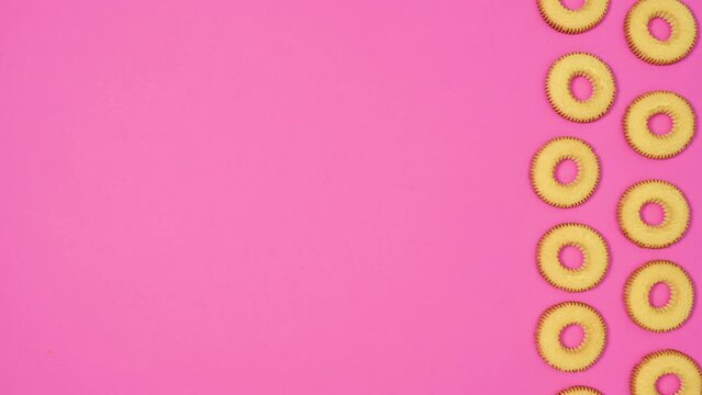 Round cookies in two columns appear on right side of vibrant pink theme. Stop motion flat lay