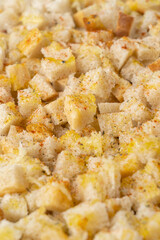 Bread cut into square slices for baking breadcrumbs in the oven, sprinkled with spices and dressed with olive oil. Selective focus, vertical photo