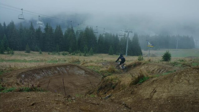 A mountain bike racer is riding down a trail very fast