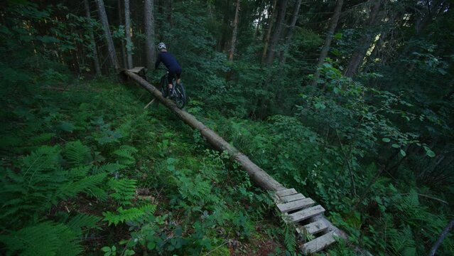 A mountain biker rides along a narrow fallen tree