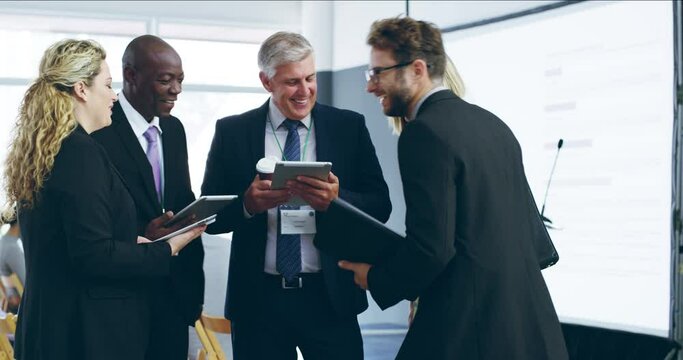 The kind of people great business networks are made of. Diverse group of business people talking and using digital tablets at a conference. Colleagues discussing work online