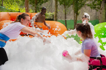 Happy friends are playing a game - who will find balls in soap suds faster. High quality photo