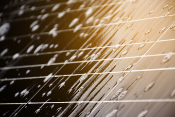 Closeup photovoltaic panel which had waterdrops and sponges on the surface, soft and selective focus, concept for using natural power in daily life around the world.