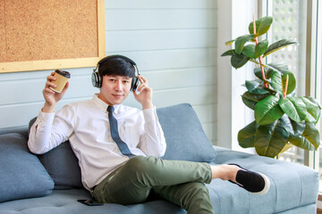 Happy businessman enjoy listening favorite music from wireless earphone with dance acting along song rhythm and drinking cup of coffee for refreshment