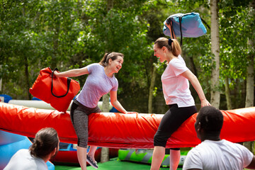 Cheerful girlfriends fighting with inflatable pillows in an amusement park. High quality photo