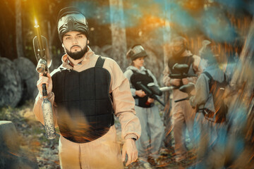Man paintball player in camouflage standing with gun before playing outdoors