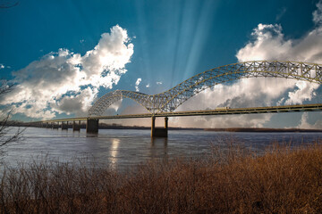 the Memphis & Arkansas Bridge over the vast flowing waters of the Mississippi river with blue sky...