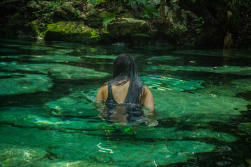 Fotografía de una chica de espaldas nadando en un cenote en quintana roo