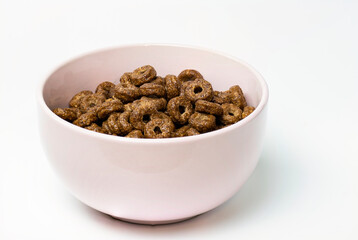A number of chocolate cereal rings on a white plate in a plate.