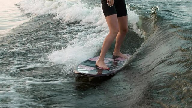 A female surfer jumping on a wakeboard. An experienced wakeboarder splashes water drops into the camera.