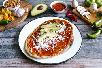 Memela sope quesadilla poblana of red sauce with cheese, onion and avocado traditional mexican food from Puebla, Mexico