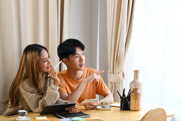 Happy young woman sitting together in living room and using digital table for shopping online.