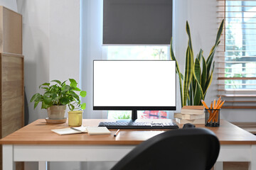 Comfortable workplace with computer pc, houseplant and supplies on wooden table.