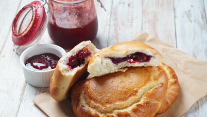 Сherry Pies stuffed with berries cherry, bowl with cherry jam. Homemade sweet pies from yeast dough freshly  baked in oven © Natalia Hanin