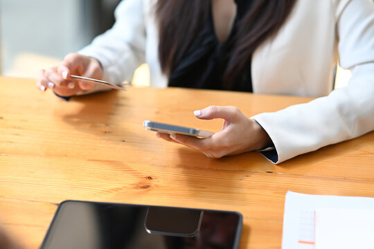 Cropped image of woman holding credit card and smart phone. E-commerce and online shopping.