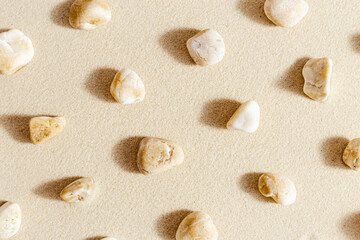 Pattern with close up pebble sea stones on sand texture. Layout from natural stone neutral natural tones. Minimal style sandy background