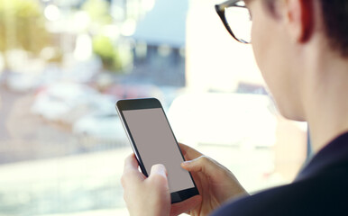 She makes herself available to her clients. Cropped shot of an unrecognizable young businesswoman using a mobile phone while standing on her office balcony.