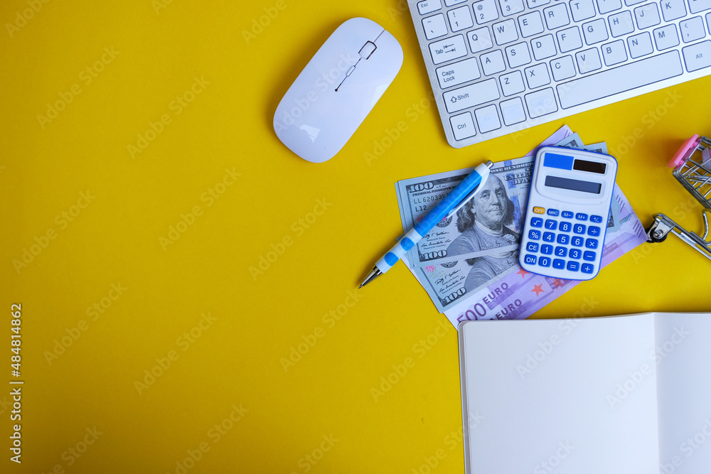 Poster blank notebook with a pen sits on an office desk table surrounded by computer tools and a range of m
