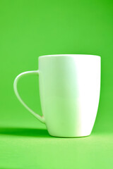 White coffee mug against vivid green background, simple and minimalistic