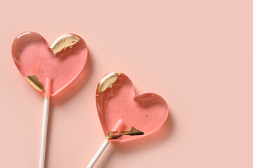 Lollipops pink candy on stick on pink background. Sweets couple. Top view. Valentine's day romantic greeting card. Copy space.