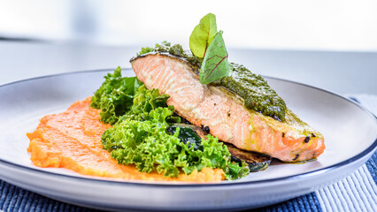A seafood dinner serving of a piece of Atlantic Salmon on top of sweet potato mash and kale.
