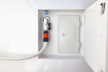 A water tap with a hose connected to it on the hull of the yacht. A place for water supply on a...