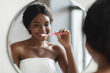 Young black woman with braces brushing her teeth