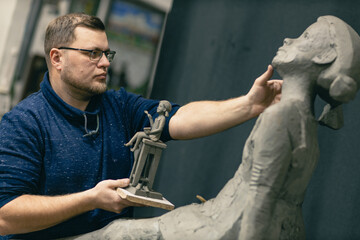 Man sculptor creates sculpt bust clay human woman sculpture. Statue craft creation workshop.