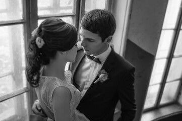 Bride and groom almost kissing indoor close to each other in passion, black and white