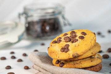 Homemade cookies with chocolate, nuts and coffee beans on a light wooden background with a linen napkin with a background blur.