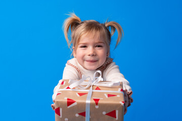 Happy little girl holding agift box on a blue background
