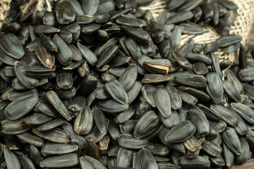 Sunflower seeds are scattered on homespun fabric with a rough texture. close-up, selective focus.