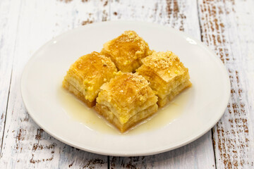 Baklava with milk (sutlu nuriye). Baklava with hazelnut and milk on a white wooden background.