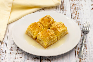Baklava with milk (sutlu nuriye). Baklava with hazelnut and milk on a white wooden background.