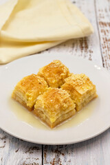 Baklava with milk (sutlu nuriye). Baklava with hazelnut and milk on a white wooden background.