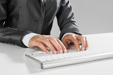Closeup of businesswoman hand typing on keyboard with mouse on wood table
