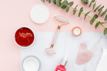 Flat lay with jade roller and Natural organic cosmetics: serum, cream on white background with green leaves. Skincare, cosmetology, dermatology concept. Beauty certificate, blog style. Top view