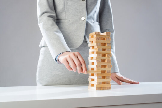 Businesswoman removing wooden block from tower