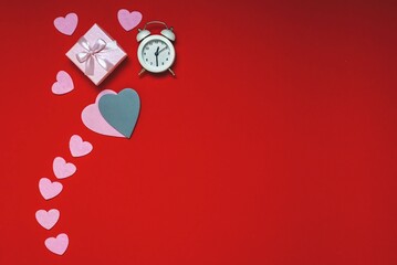 Top view of workspace time for valentines day flat lay on red background, heart gifts and alarm clock, copy space