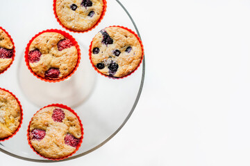 Freshly baked oatmeal fruit cupcakes in red silicon rubber cooking molds, displayed on a serving plate, on kitchen table. Children friendly homemade food. Sugar-free cookies.  Food flat lay
