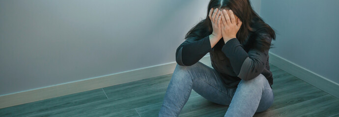 Depressed woman with hands in face sitting on the floor