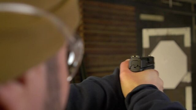 The shooter fires a pistol at a paper target, close-up, focus on the rear sight, the camera moves, soft focus